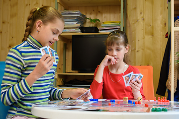 Image showing A girl plays a card from her hand, another girl looks thoughtfully