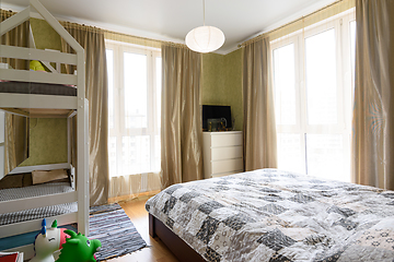 Image showing Bedroom interior with large double bed, bunk cot and two large stained glass windows