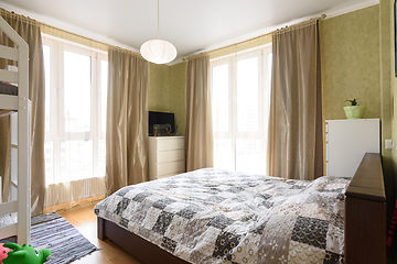 Image showing Interior of a bright bedroom with a large double bed and two large stained glass windows