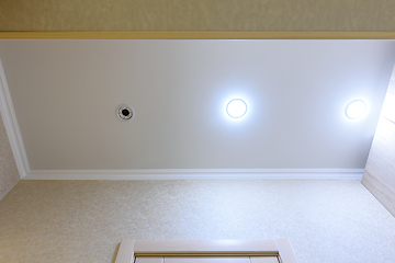 Image showing Stretch white matte ceiling in the hallway, one of the lamps burned out and twisted