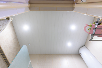 Image showing Bathroom ceiling made of white metal panels, with built-in lights, one of which has burned out