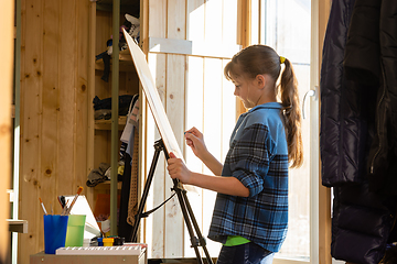 Image showing A ten-year-old girl makes a sketch on an easel, removes unnecessary details with a washing eraser