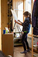 Image showing A ten-year-old girl draws with paints on an easel at home