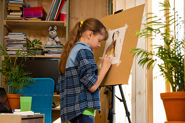 Image showing Girl draws a cat on an easel in her room at home