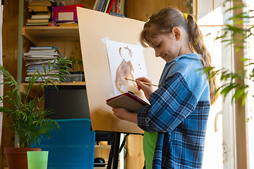 Image showing A ten-year-old girl watches a video tutorial and draws a picture on a tablet