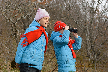 Image showing Girlfriend tells another girlfriend what she saw through binoculars