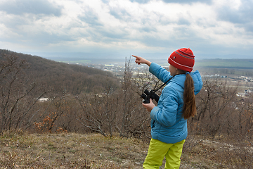 Image showing The girl saw something through binoculars, looking at the mountains and points there with her finger