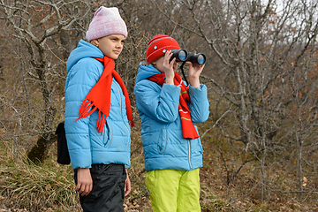Image showing The girl looks with enthusiasm through binoculars, another girl is standing nearby and looks in the same direction