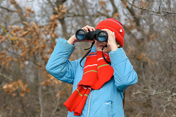 Image showing Girl enthusiastically looks through binoculars, front view, close-up