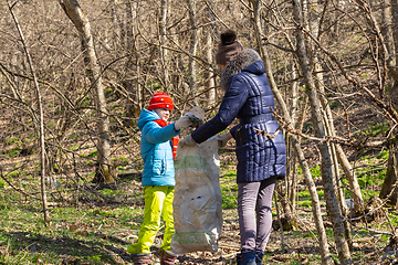 Image showing A girl collects garbage in the forest, a girl holds a large garbage bag