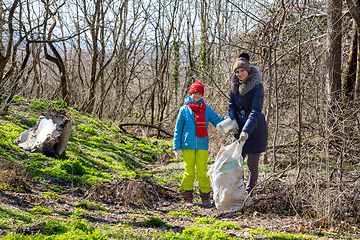 Image showing A girl and her daughter collect garbage in the forest in early spring, they looked into the frame