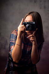 Image showing Girl photographer takes pictures with a retro camera, half-length studio portrait on a gray background