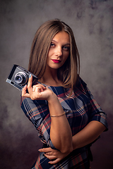 Image showing Portrait of a beautiful girl with a camera in her hands, half-length studio portrait on a gray background