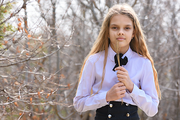 Image showing A girl stands with dried wildflowers on the background of a spring forest