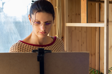 Image showing Portrait of an artist at work, a girl draws a drawing on an easel by the window, close-up