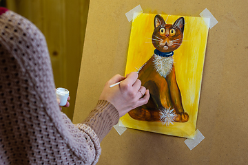 Image showing The artist draws a drawing on an easel, on the artist\'s hands and a drawing