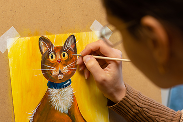 Image showing The artist draws with acrylic paints a drawing of a cat on an easel, close-up