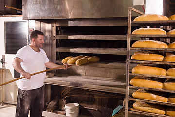 Image showing bakery worker taking out freshly baked breads