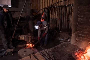 Image showing blacksmith workers using mechanical hammer at workshop