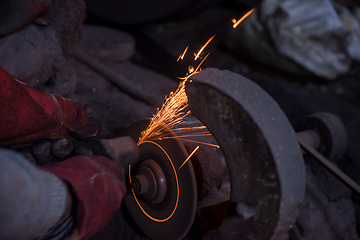 Image showing the blacksmith polishing metal products