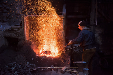 Image showing young traditional Blacksmith working with open fire