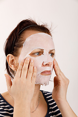 Image showing housewife woman with a sheet mask on her face