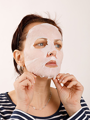 Image showing housewife woman with a sheet mask on her face