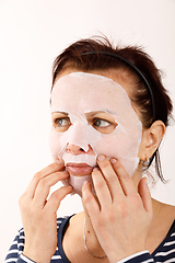 Image showing housewife woman with a sheet mask on her face
