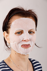 Image showing housewife woman with a sheet mask on her face