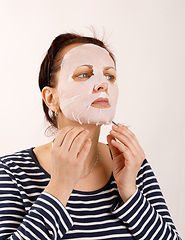 Image showing housewife woman with a sheet mask on her face