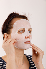 Image showing housewife woman with a sheet mask on her face