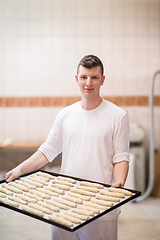 Image showing A young baker holding raw product of white dough