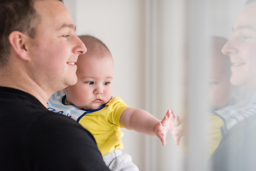 Image showing young father holding baby near the window at home