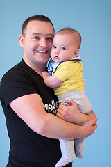 Image showing portrait of happy young father holding baby isolated on blue