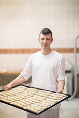 Image showing A young baker holding raw product of white dough