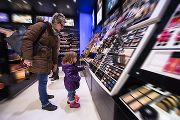 Image showing young mother and her little daughter buying makeup