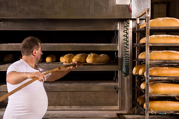 Image showing bakery worker taking out freshly baked breads