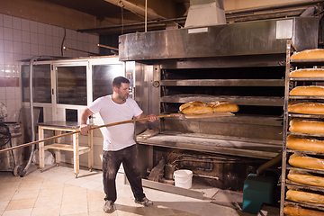 Image showing bakery worker taking out freshly baked breads