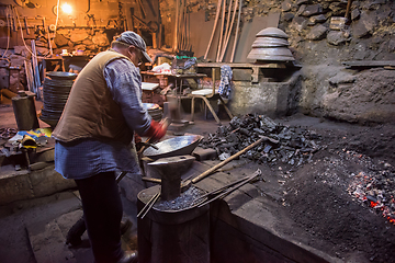 Image showing traditional blacksmith manually forging the molten metal