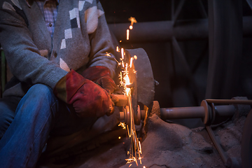 Image showing the blacksmith polishing metal products