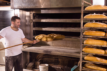 Image showing bakery worker taking out freshly baked breads