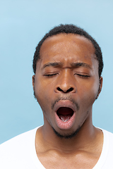 Image showing Close up portrait of young man on blue background.