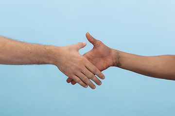 Image showing Close up shot of human holding hands isolated on blue studio background.