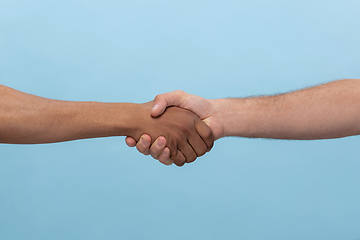 Image showing Close up shot of human holding hands isolated on blue studio background.