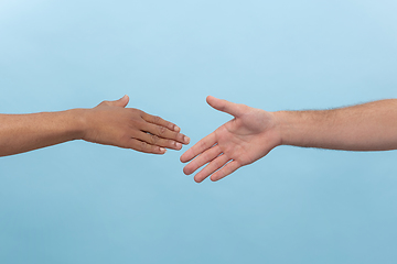 Image showing Close up shot of human holding hands isolated on blue studio background.