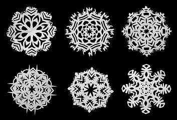 Image showing Snowflakes cut out of white paper. Black background