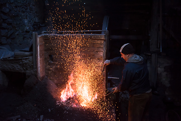 Image showing young traditional Blacksmith working with open fire