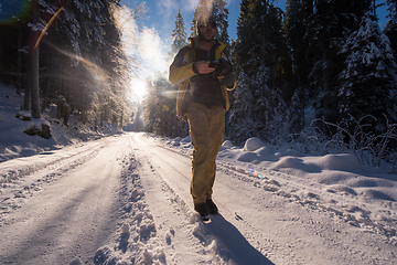 Image showing young photographer walking on snowy country road