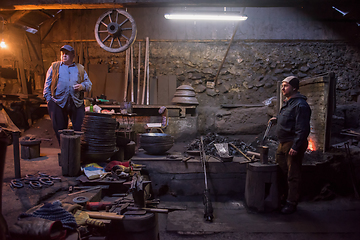 Image showing portrait of two generations traditional blacksmith