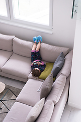 Image showing little girl using a smartphone on the sofa at home